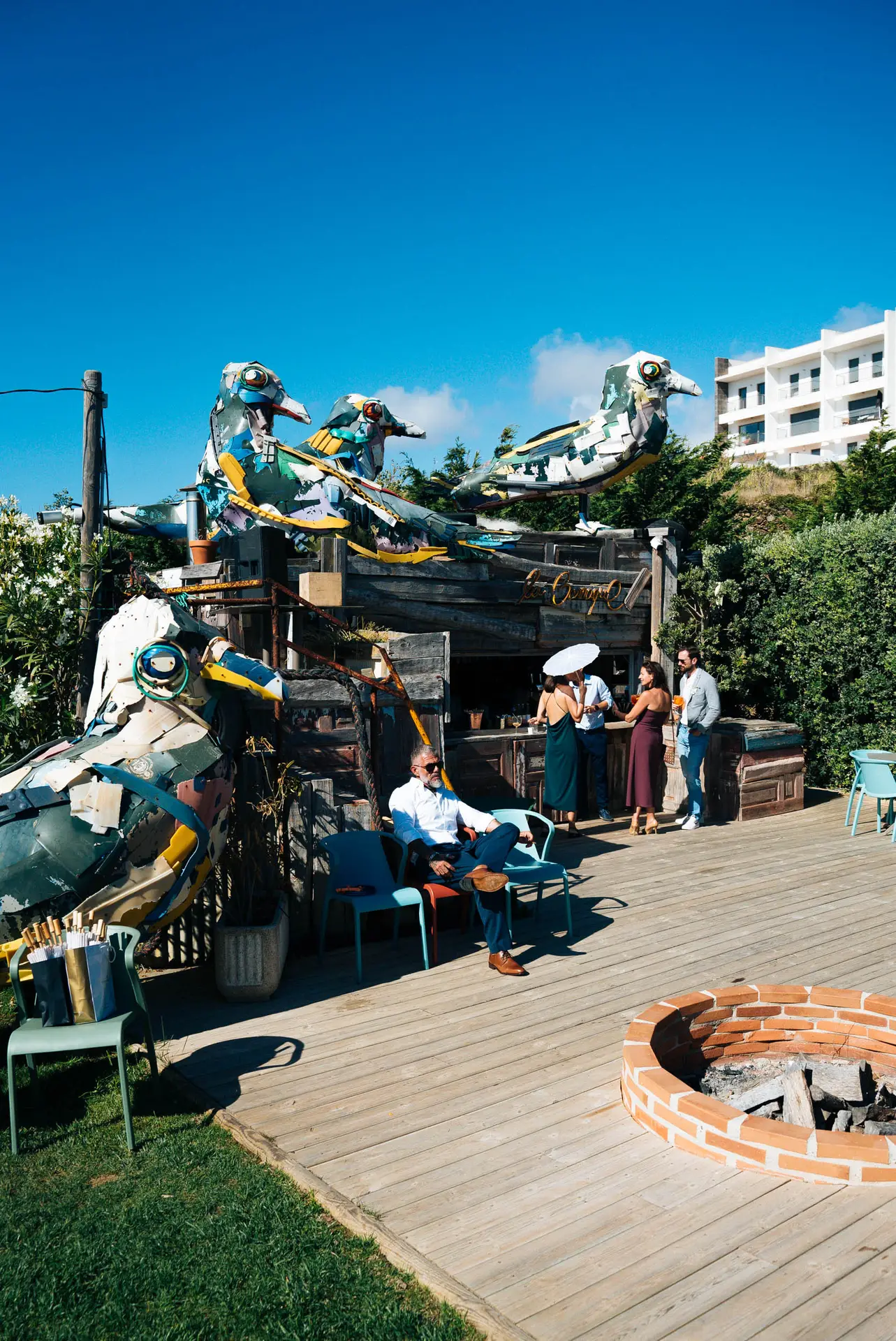 Os pássaros coloridos do Bordalo II em cima do bar La Barraque, com convidados no deck