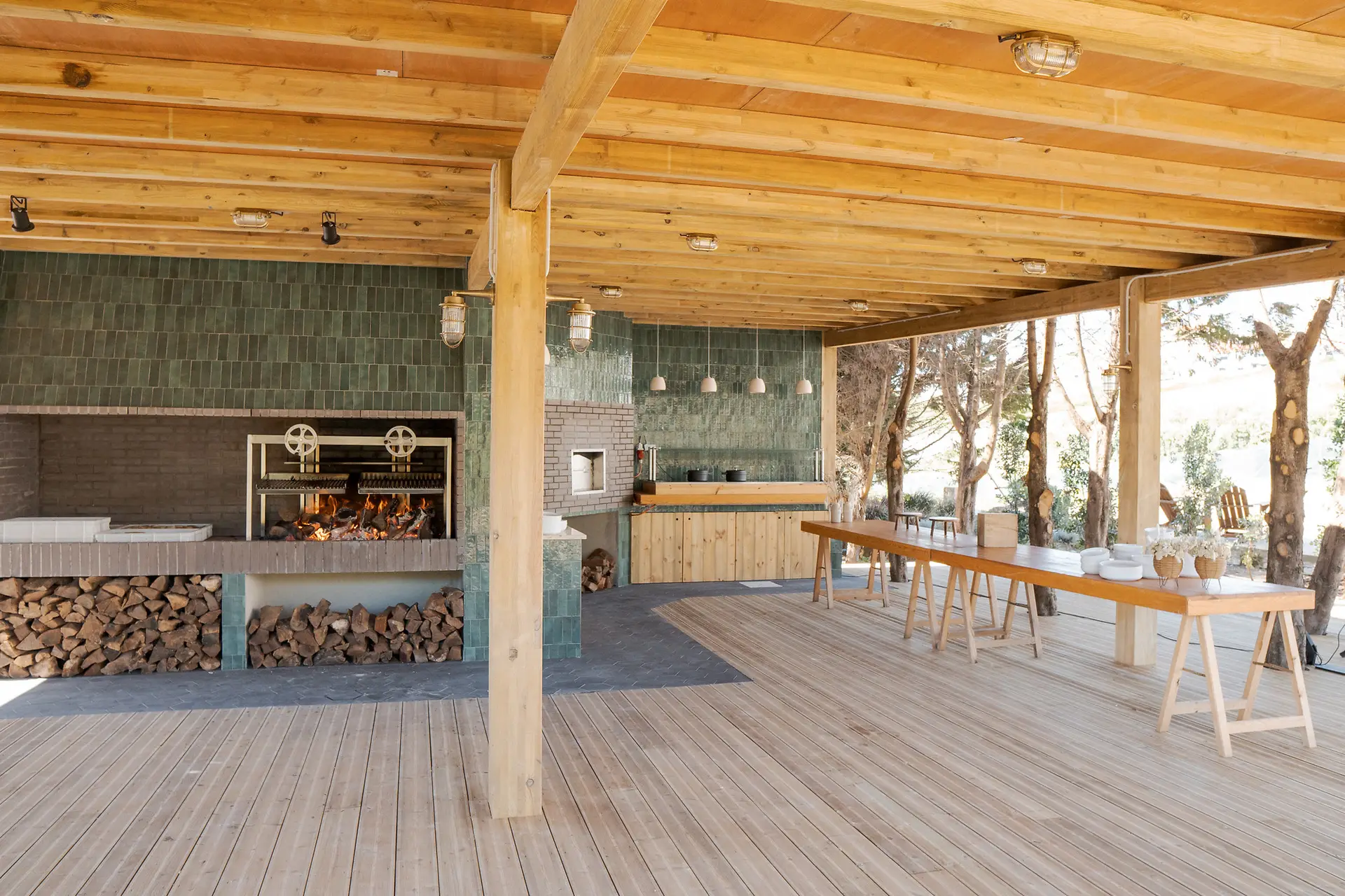 A cozinha exterior de grelha do La Barraque, com azulejos verdes e mesas corridas no deck