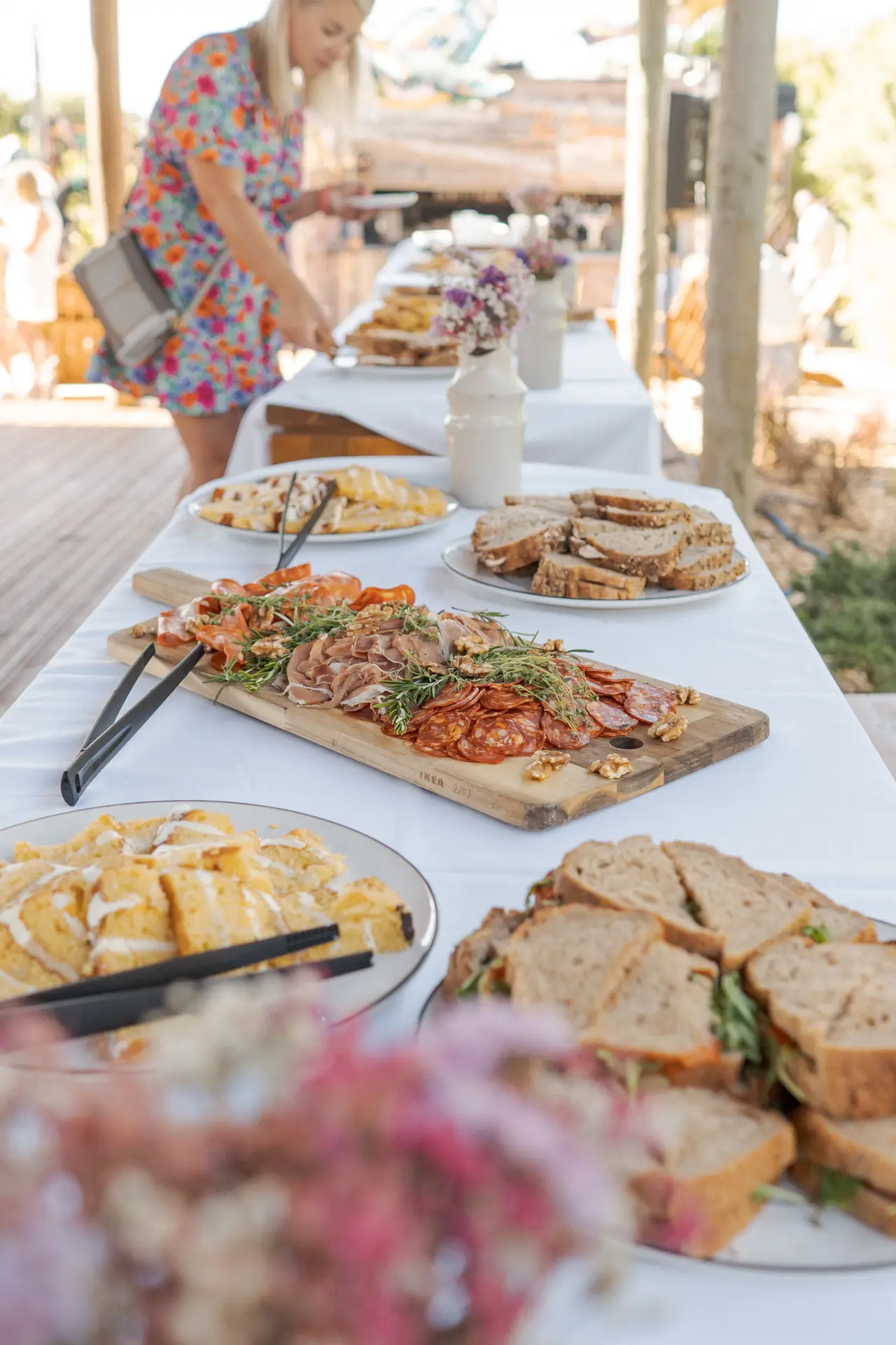 Mesa de buffet com tábua de enchidos, sanduíches e queijos