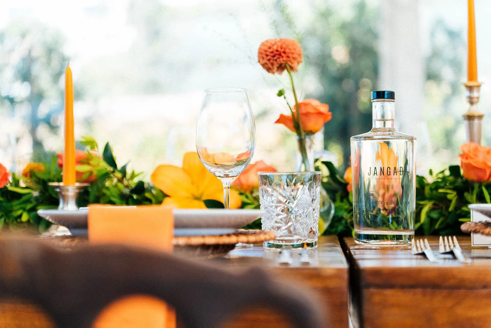 Mesa posta com velas, flores cor de laranja e guardanapos de linho