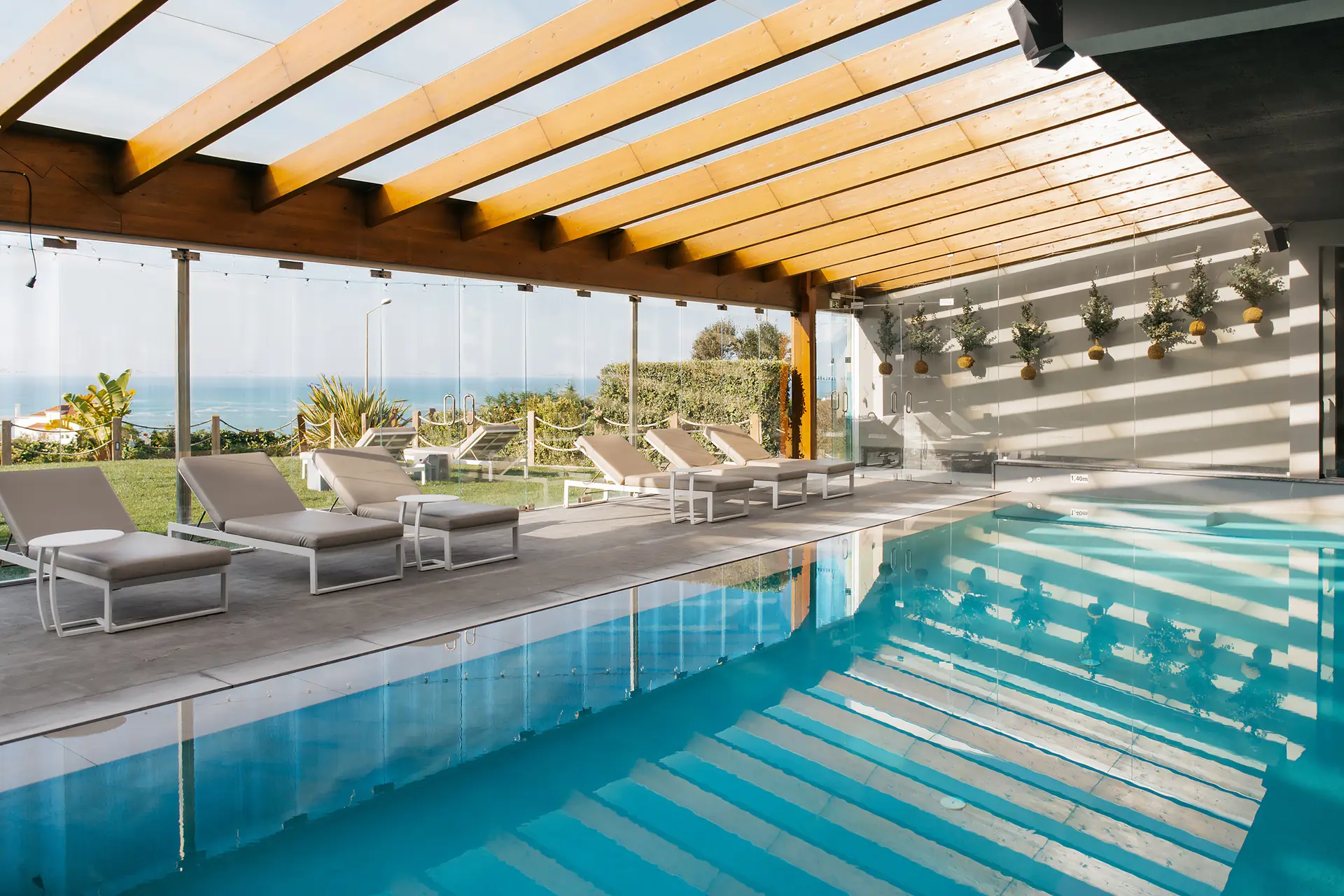 Piscina interior com espreguiçadeiras e vista para o mar