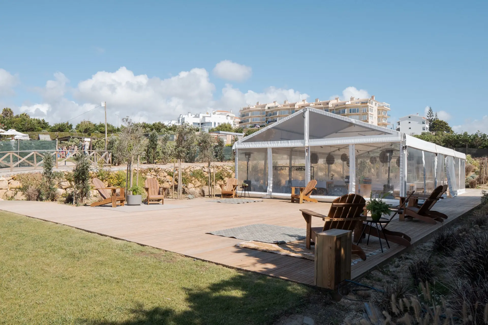 A tenda junto ao relvado, com espreguiçadeiras de madeira no deck